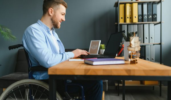 Young man with special needs in casual clothes working on wireless laptop.